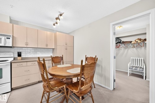Kitchen dining area featuring white appliances, light-toned cabinetry, subway tile backsplash, and track lighting - #216 17003 67 Av Nw, Edmonton, AB - Indoor