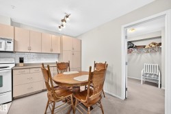 Kitchen dining area featuring white appliances, light-toned cabinetry, subway tile backsplash, and track lighting - 