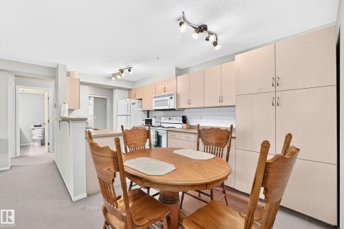 Galley kitchen featuring light wood-finish cabinetry, white subway tile backsplash, and light-toned countertops - #216 17003 67 Av Nw, Edmonton, AB - Indoor Photo Showing Other Room