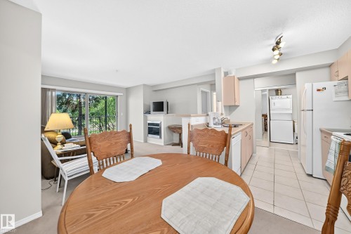 Kitchen featuring light wood-finish cabinetry, white appliances, and tile flooring - #216 17003 67 Av Nw, Edmonton, AB - Indoor