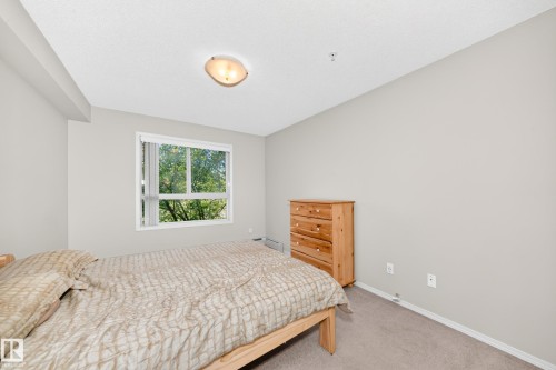 Recessed ceiling light, flush-mount ceiling light fixture, large window, light-colored walls, carpeted flooring - #216 17003 67 Av Nw, Edmonton, AB - Indoor Photo Showing Bedroom