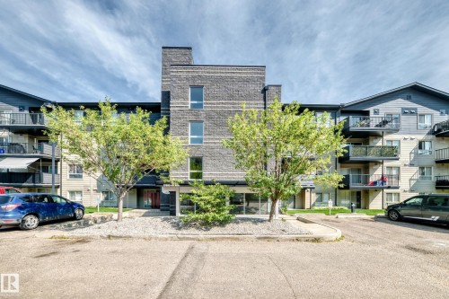 Multi-story building featuring dark grey siding and stone veneer accents - #216 17003 67 Av Nw, Edmonton, AB - Outdoor With Balcony With Facade