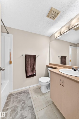 Bathroom featuring a vanity with a drop-in sink, wall-mounted mirror, and overhead lighting - #216 17003 67 Av Nw, Edmonton, AB - Indoor Photo Showing Bathroom