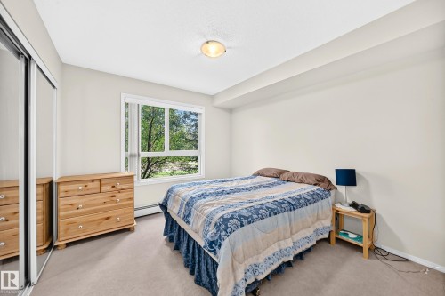Carpeted flooring, white walls, built-in mirrored closet, and a surface-mounted ceiling light fixture - #216 17003 67 Av Nw, Edmonton, AB - Indoor Photo Showing Bedroom