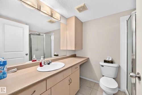 Extended vanity with integrated sink, chrome faucet, and ample storage cabinetry - #216 17003 67 Av Nw, Edmonton, AB - Indoor Photo Showing Bathroom