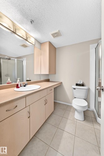 Vanity with built-in cabinetry, an integrated sink, and an expansive countertop - #216 17003 67 Av Nw, Edmonton, AB - Indoor Photo Showing Bathroom