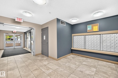 Tiled flooring, overhead lighting, glass entry doors, and a built-in mail center - #216 17003 67 Av Nw, Edmonton, AB - Indoor Photo Showing Other Room