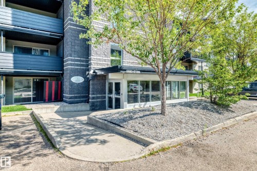 Multi-story building exterior with dark gray siding, an accessible entry ramp, and an entry canopy - #216 17003 67 Av Nw, Edmonton, AB - Outdoor