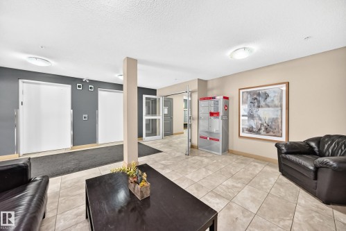 Tiled flooring in a common area with recessed lighting, integrated mailboxes, and an entry door with glass panels - #216 17003 67 Av Nw, Edmonton, AB - Indoor