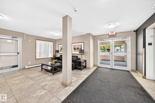 Tiled flooring, double glass entry doors, large window, built-in lighting, and an elevator - #216 17003 67 Av Nw, Edmonton, AB - Indoor