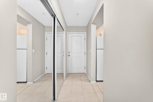 Tile flooring, mirrored closet doors, paneled interior doors, recessed lighting, and a white refrigerator - #216 17003 67 Av Nw, Edmonton, AB - Indoor Photo Showing Other Room