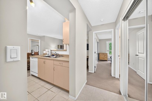 Kitchenette with light wood-finish cabinetry, integrated dishwasher, and tile flooring - #216 17003 67 Av Nw, Edmonton, AB - Indoor