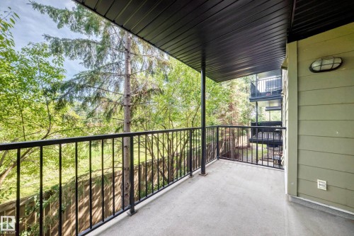 Private balcony featuring a concrete surface, black metal railing, and a black paneled ceiling - #216 17003 67 Av Nw, Edmonton, AB - Outdoor With Balcony With Exterior