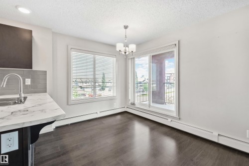 Wood-finish flooring, white walls, and a sliding glass door to a balcony - #318 5521 7 Av Sw Sw, Edmonton, AB - Indoor Photo Showing Other Room