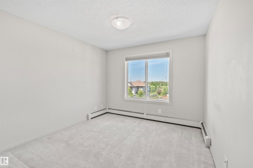 Light gray wall finishes with a window providing exterior scenery, accompanied by light gray carpet flooring - #318 5521 7 Av Sw Sw, Edmonton, AB - Indoor Photo Showing Other Room