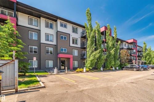 Modern apartment building featuring a multi-tone facade, private balconies with glass railings, and a surface parking area - #318 5521 7 Av Sw Sw, Edmonton, AB - Outdoor With Facade