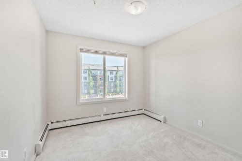 Light-colored walls, carpet flooring, a window with white trim, and a ceiling-mounted light fixture - #318 5521 7 Av Sw Sw, Edmonton, AB - Indoor Photo Showing Other Room