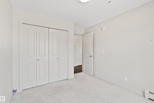 Neutral wall paint, carpeted flooring, bi-fold closet doors, and interior paneled door - #318 5521 7 Av Sw Sw, Edmonton, AB - Indoor