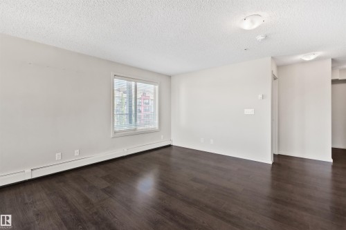 Bright and open living space showcasing gleaming dark wood-finish flooring, recessed ceiling lighting, and large windows allowing abundant natural light - #318 5521 7 Av Sw Sw, Edmonton, AB - Indoor Photo Showing Other Room