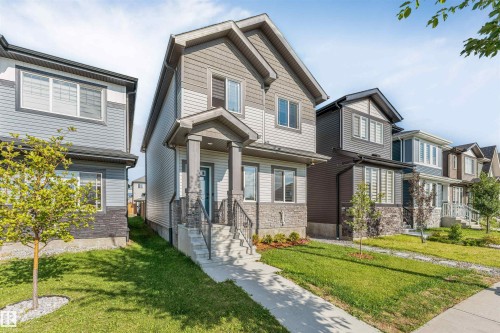 Two-story residential architecture with a covered front porch, stone and siding exterior, and a concrete pathway - 1263 Watt Drive Sw, Edmonton, AB - Outdoor With Facade