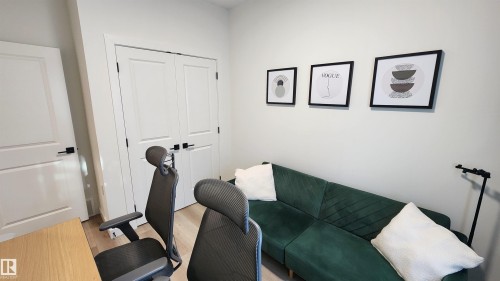 Light wood-finish flooring, white walls, and white paneled doors with matte black hardware - 220 28 Street Sw, Edmonton, AB - Indoor Photo Showing Gym Room
