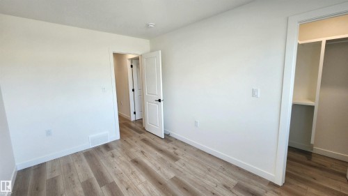 Wood-finish flooring, white walls, white trim, and a built-in closet with shelving - 220 28 Street Sw, Edmonton, AB - Indoor Photo Showing Other Room