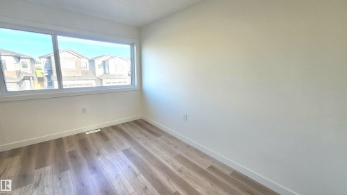 Wood-finish flooring, white walls, and a large window - 220 28 Street Sw, Edmonton, AB - Indoor Photo Showing Other Room