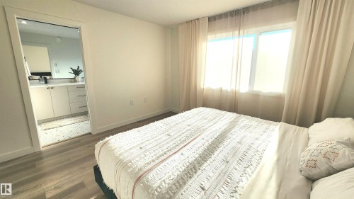 Wood-finish flooring, white walls, and a window with neutral drapes - 220 28 Street Sw, Edmonton, AB - Indoor Photo Showing Bedroom