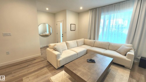 Wood-finish flooring, recessed lighting, and a large window with sheers - 220 28 Street Sw, Edmonton, AB - Indoor Photo Showing Living Room