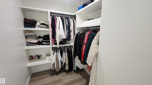 Custom closet system featuring built-in shelving, multiple hanging rods, and wood-finish flooring - 220 28 Street Sw, Edmonton, AB - Indoor With Storage