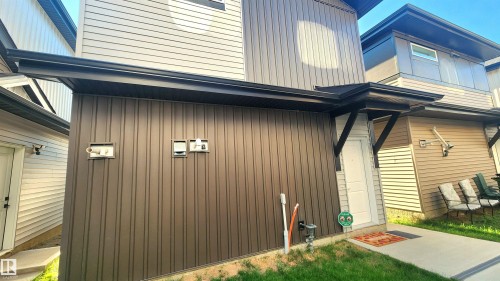 Vertical siding on a structure with black trim and a concrete walkway - 220 28 Street Sw, Edmonton, AB - Outdoor With Exterior