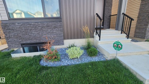 Stacked stone accent wall, metal exterior siding, concrete steps, and black metal railings - 220 28 Street Sw, Edmonton, AB - Outdoor