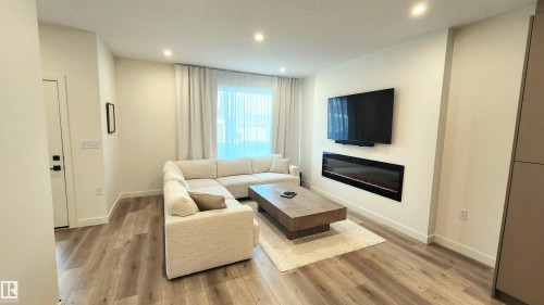 Living area with wood-finish flooring, recessed lighting, and an electric fireplace - 220 28 Street Sw, Edmonton, AB - Indoor Photo Showing Living Room With Fireplace