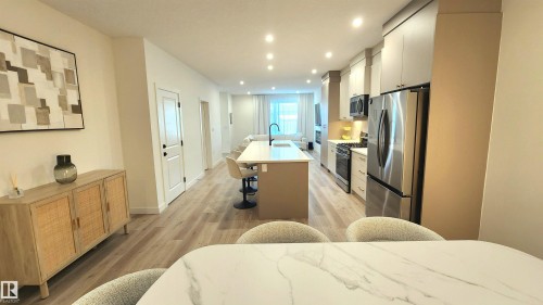Open-concept living area featuring wood-finish flooring, recessed lighting, and a kitchen with stainless steel appliances - 220 28 Street Sw, Edmonton, AB - Indoor