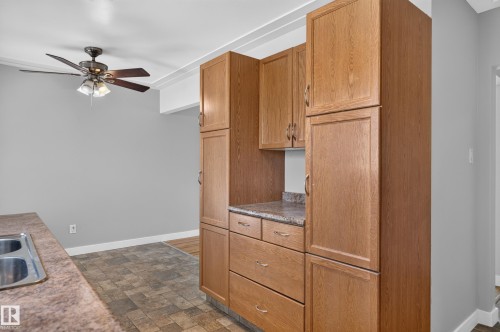 Wood-finish cabinetry with silver-tone hardware, granite-look countertops, and tile flooring - 13214 123 Street Nw, Edmonton, AB 