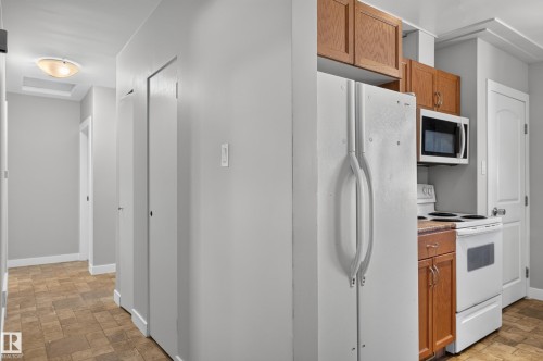 Kitchenette area featuring wood cabinetry, white appliances, and a built-in microwave - 13214 123 Street Nw, Edmonton, AB 