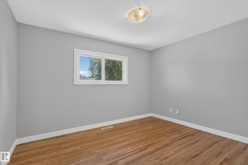 Hardwood flooring, neutral gray wall tones, ceiling-mounted light fixture, white window trim, and white baseboards - 13214 123 Street Nw, Edmonton, AB 