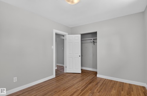 Wood-finish flooring, light gray walls, built-in closet with shelving, white trim, and a ceiling-mounted light fixture - 13214 123 Street Nw, Edmonton, AB 