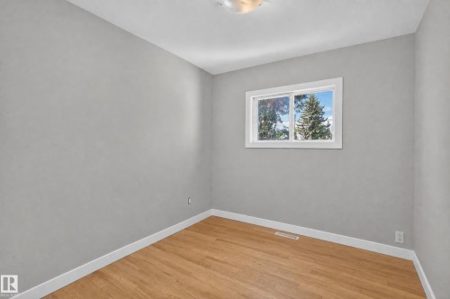Light gray walls, wood-finish flooring, white trim, and a window with white casing - 13214 123 Street Nw, Edmonton, AB 