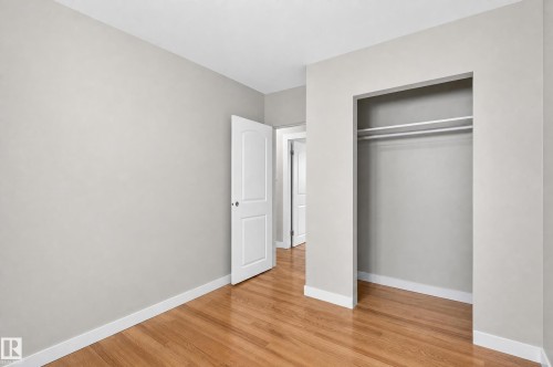 Hardwood flooring, painted walls, open closet with hanging rods, and a paneled interior door - 13214 123 Street Nw, Edmonton, AB 