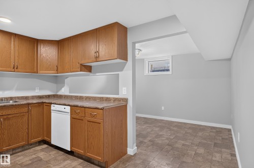 Kitchen featuring wood-finish cabinetry, a white dishwasher, and laminate countertops - 13214 123 Street Nw, Edmonton, AB 