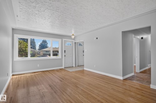 Hardwood flooring, light gray wall finishes, white trim, a large multi-pane window, and a white entry door with a frosted glass insert - 13214 123 Street Nw, Edmonton, AB 