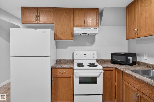 Kitchen featuring wood cabinetry, white refrigerator, white electric range, and a dual basin sink - 13214 123 Street Nw, Edmonton, AB 