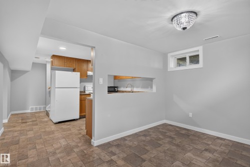 Recessed kitchen area with wood-finish cabinetry and a white refrigerator - 13214 123 Street Nw, Edmonton, AB 