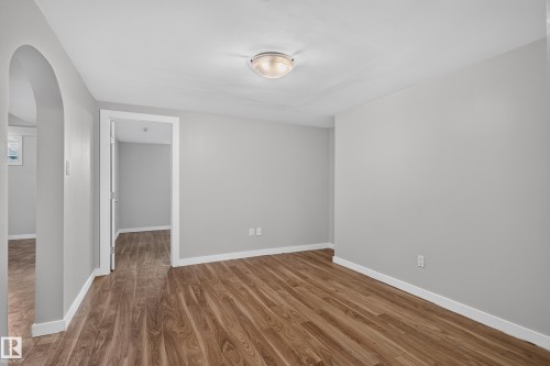 Wood-finish flooring throughout, complemented by a hallway archway and flush-mount ceiling lighting - 13214 123 Street Nw, Edmonton, AB 