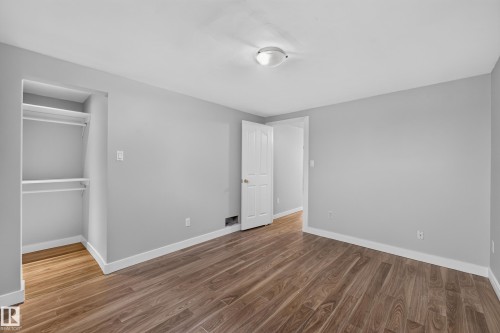 Wood-finish flooring, light gray wall tones, ceiling-mounted lighting, white trim, and built-in closet shelving - 13214 123 Street Nw, Edmonton, AB 