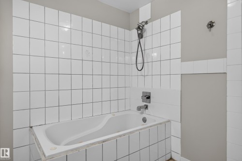 Bathtub with white tile surround and wall-mounted shower fixture - 13214 123 Street Nw, Edmonton, AB 