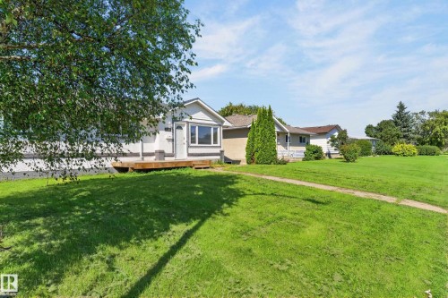Single-story residence featuring light-colored siding, a front entry deck, and a bay window - 13214 123 Street Nw, Edmonton, AB 