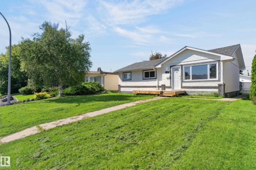 White exterior with textured dark grey trim, white framed windows, and a wood-toned front deck - 13214 123 Street Nw, Edmonton, AB 