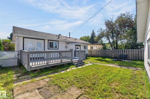 Spacious deck with wood railing, double French doors, and steps leading to a grass yard - 13214 123 Street Nw, Edmonton, AB 
